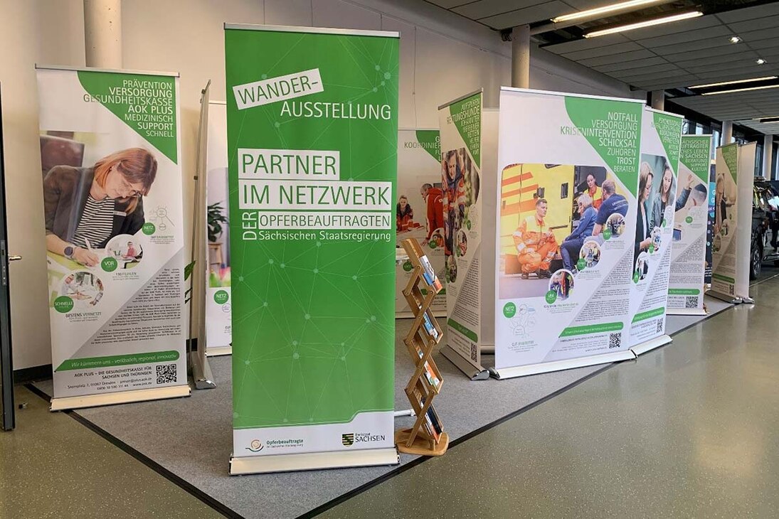 Roll-ups der Wanderausstellung der Sächsischen Opferbeauftragten 2023 auf einer Ausstel-lungsfläche der Messe FLORIAN, einander gereiht mit Texten und Bildern zu Hilfeangeboten für Betroffene.