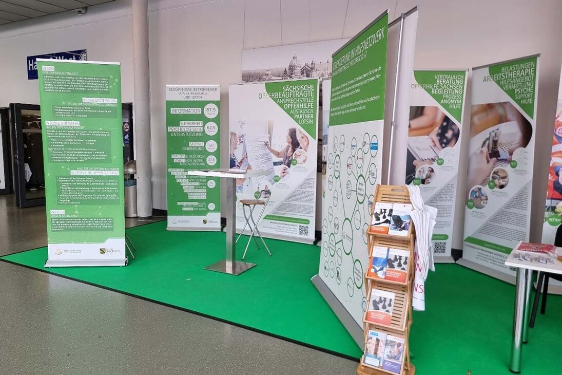 Roll-ups der Wanderausstellung der Sächsischen Opferbeauftragten 2023 auf einer Ausstel-lungsfläche der Messe FLORIAN, einander gereiht mit Texten und Bildern zu Hilfeangeboten für Betroffene.